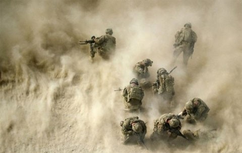 Binh sĩ Mỹ tập trung gần một chiếc xe bị phá hủy. Họ cùng nhau che mặt vì gió từ cánh quạt của một chiếc trực thăng thổi tung cát bụi ở bên dưới. Các đồng đội bị thương của các binh sĩ này đang được một trực thăng cứu thương đưa từ Lữ đoàn Đặc nhiệm Sấm sét thứ 159 tới bệnh viện ở Kandahar, thành phố lớn thứ hai của Afghanistan, hôm 23/8. Ba binh sĩ Mỹ đã bị thương sau khi xe của họ bị trúng một quả bom tự tạo ven đường. Ảnh: AFP